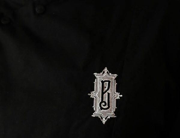logo argenté de la Boulangerie Baptiste sur un veste de cuisine noire