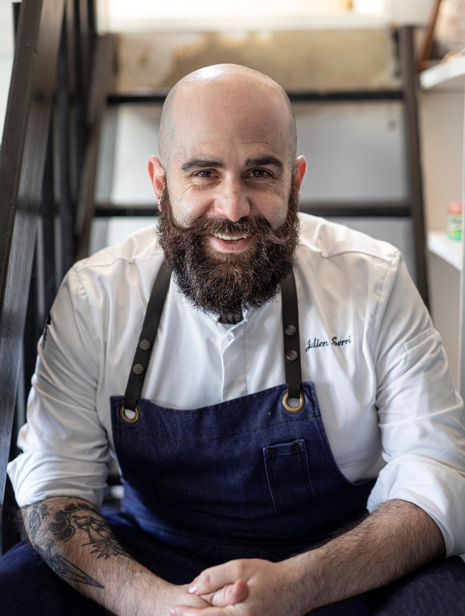 Portrait Julien Serri, crâne rasé et grande barbe souriante