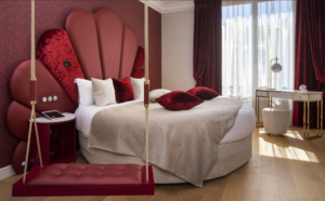 chambre au thème romantique avec des murs pourpres, du rouge, du blanc et du bordeaux ainsi qu'une balançoire dans la chambre