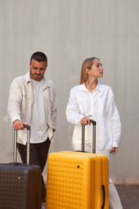 un homme et une femme on chacun une valise et regarde autour d'eux