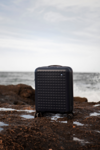 Dot-Drops : valise noire sur une falaise au bord de mer