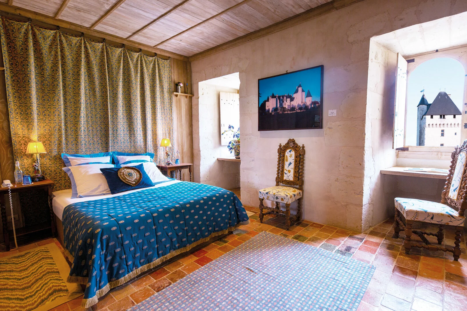 grande chambre en pierres. Le lit a une parure bleue, dans un style médiéval. grande chambre en pierres. Le lit a une parure bleue, dans un style médiéval.