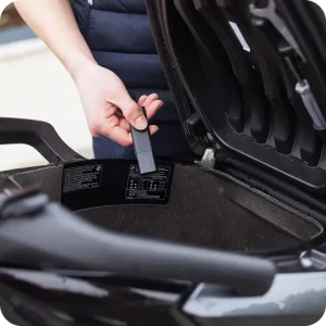 main plaçant un tracker GPS Invoxia dans le coffre d’un scooter pour le sécuriser