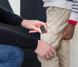 main plaçant un tracker Invoxia dans la poche d’un enfant pour assurer sa sécurité