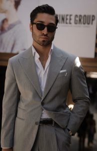 Homme portant un costume gris à fines rayures et chemise blanche, look Hockerty au Pitti Uomo 108 à Florence.