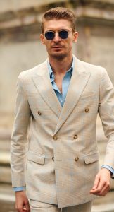 Homme en costume croisé beige à carreaux bleus et chemise bleu ciel, présenté par Hockerty au Pitti Uomo 108.