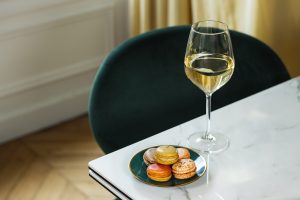 assiette de macarons de Franck Deville avec verre à vin sur une table blanche