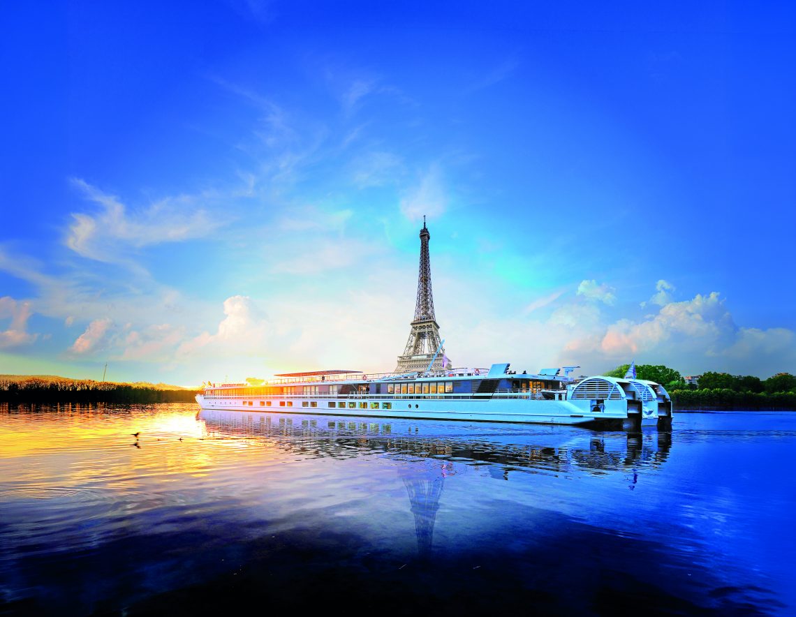 Bateau sur fleuve calme, avec Tour Eiffel centrée au fond avec un soleil couchant. Ciel est très bleu.