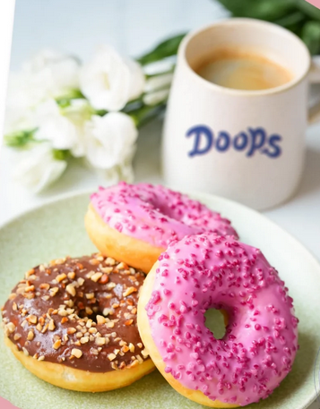 Présentation de trois donuts DOOPS dans une assiette : deux pinkframboise et un coconuts