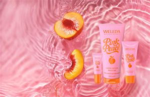 Produit weleda rose sur fond rose aquatique et morceau de pêches